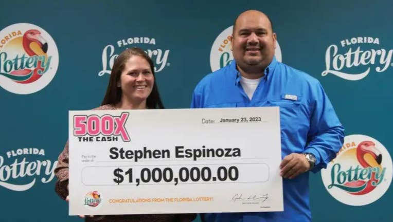 Stephen Espinoza holds a giant $1 million check from the Florida Lottery after buying a winning scratch-off ticket from a Publix supermarket.