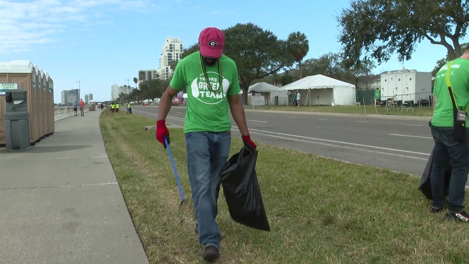 A volunteers picks up beans and other trash left behind during Gasparilla.