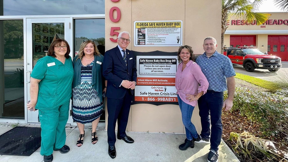 Officials pose next to the Safe Haven Baby Box on the outside of the fire station in Ocala, Florida.