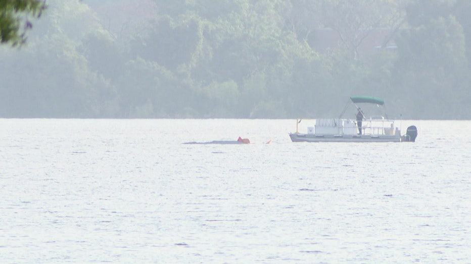 A boat near a partially submerged plane following crash.