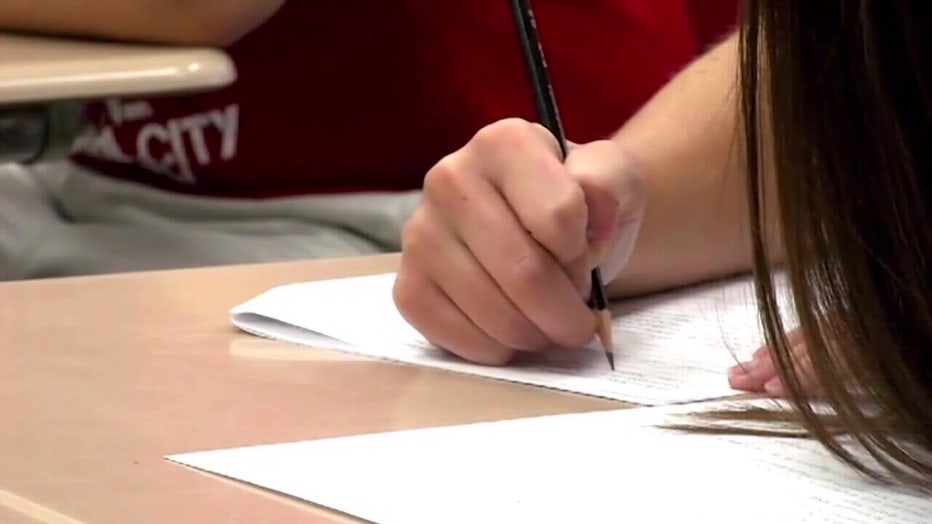 File: Student writing on paper in school. 