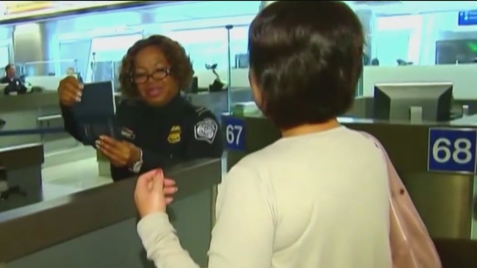 File: A security officer checks a traveler's passport. 