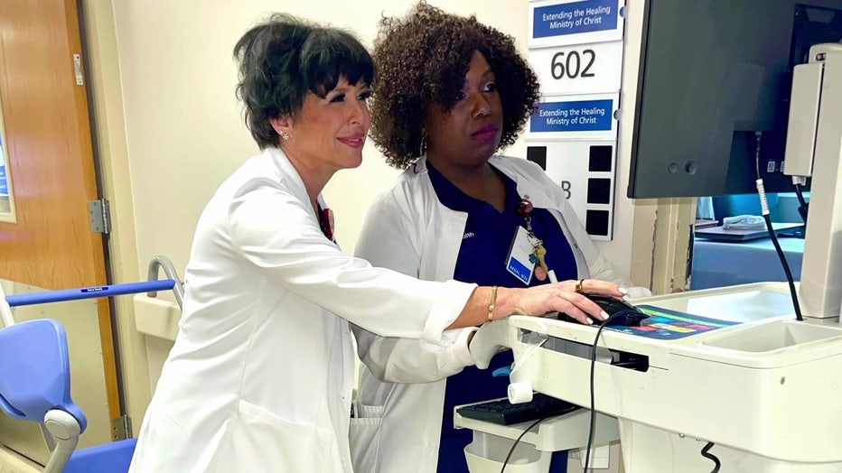 Two healthcare workers look at electronic chart.
