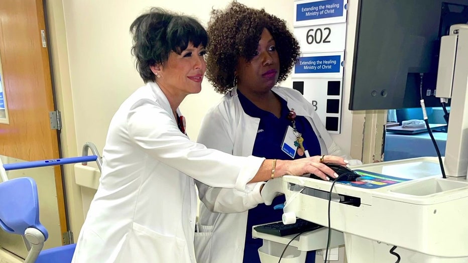 Two healthcare workers look at electronic chart. 