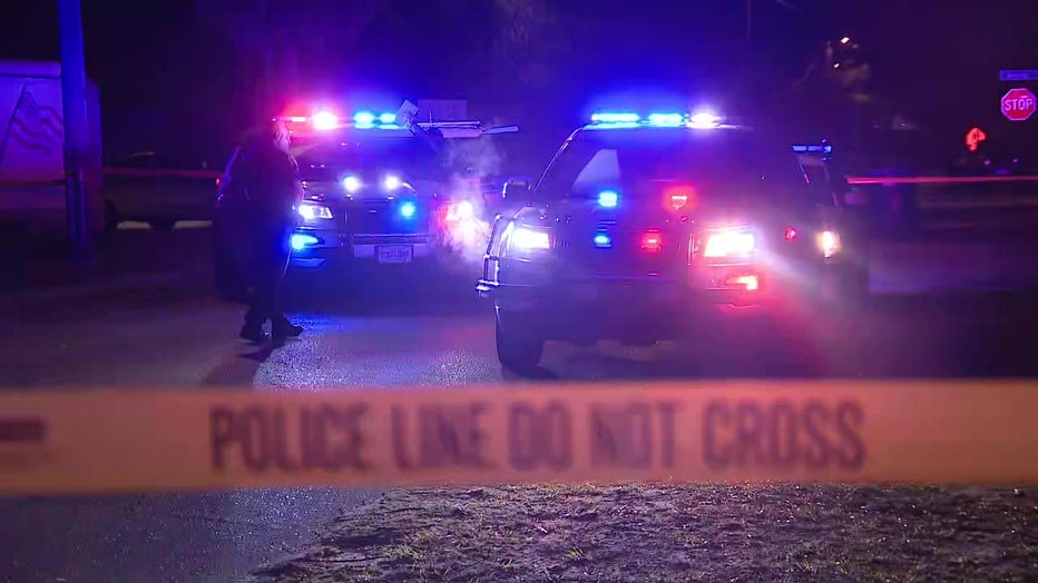 Crime scene tape and police cars outside shooting scene.