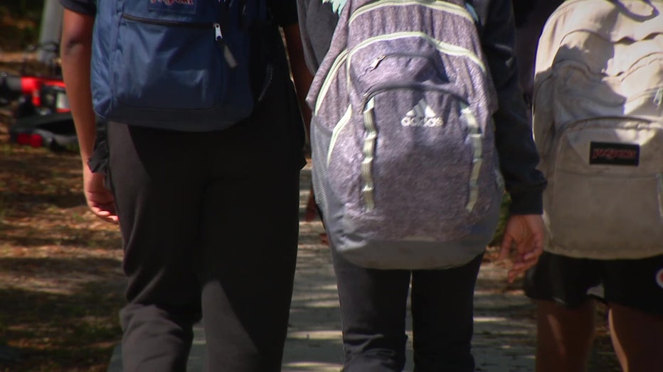 Students walk with backpacks outside of school. 