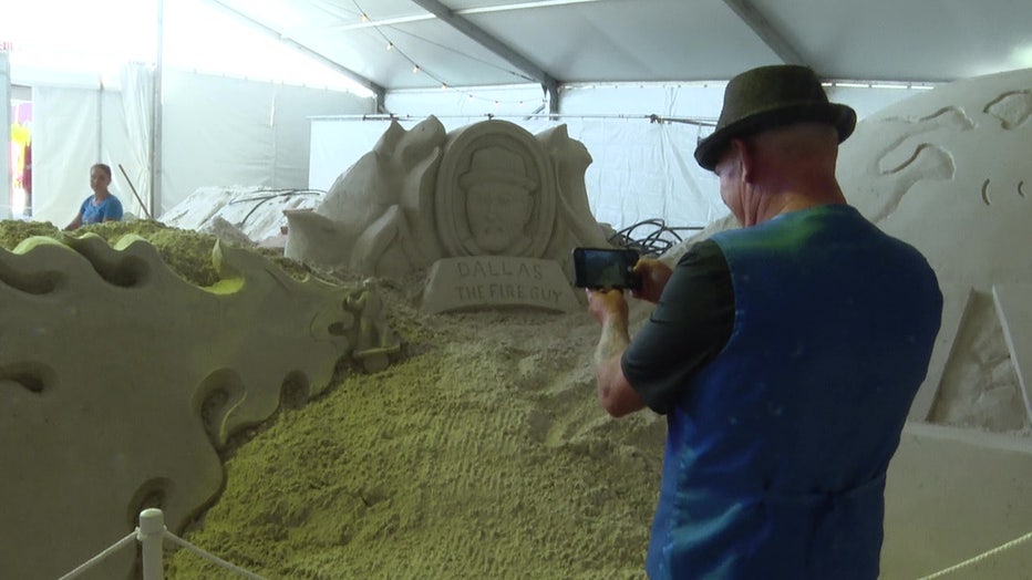 Dallas Saupe takes a photo of the sand sculpture dedicated to him. 
