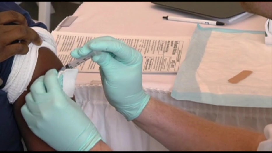 File: Healthcare worker giving someone a vaccine. 