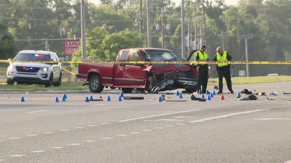 Investigators surround a red pick-up truck that was involved in a double-fatal crash early Tuesday morning.