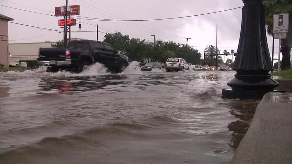 Vehicles drive through flooded street.