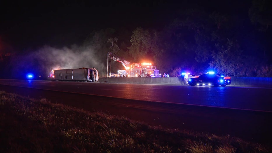 Law enforcement vehicles next to an overturned Greyhound bus. 