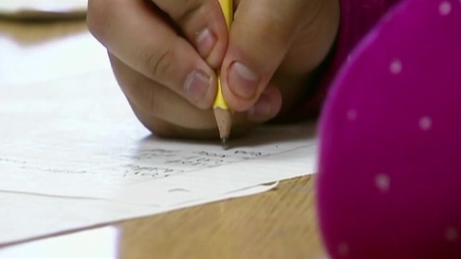 Student taking notes with pencil in class. 