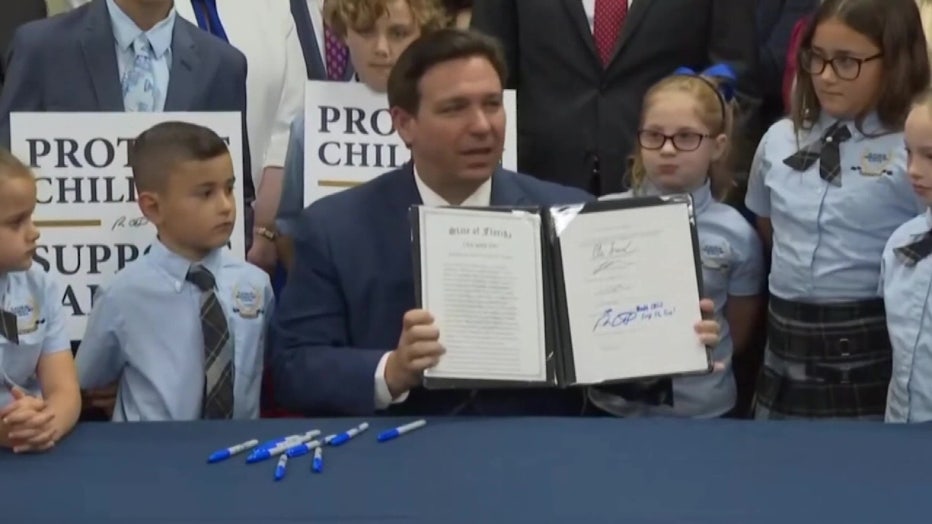 Florida Governor Ron DeSantis signs bill surrounded by children. 