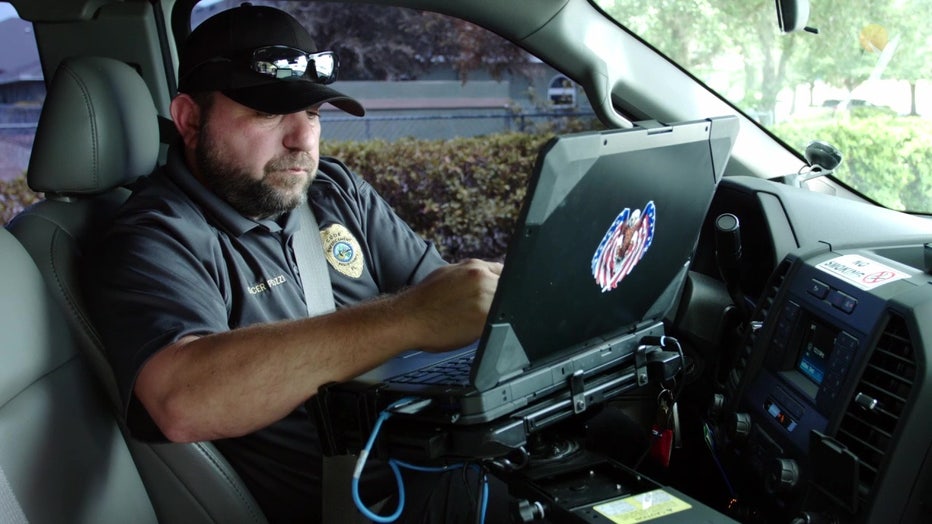 Pasco County code enforcement officer makes note on computer in vehicle. 
