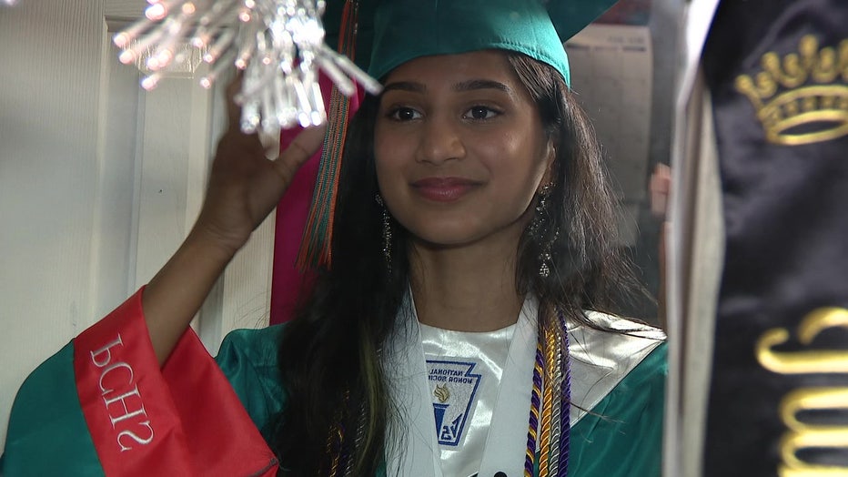 Tina Kumar checks out her cap and gown in the mirror.