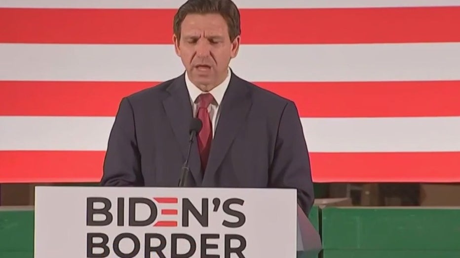 Ron DeSantis at podium speaking about illegal immigration.