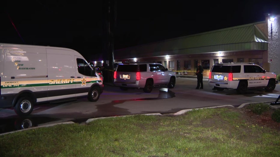 Crime scene tape and law enforcement vehicles at murder scene. 