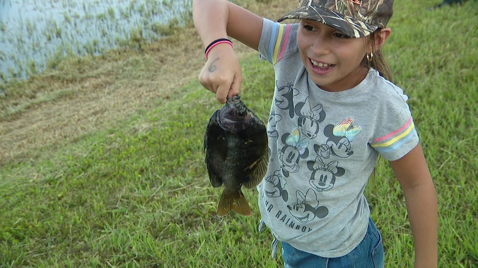 A girl holds a up a fish she caught during a Fishin' with Judd event. 
