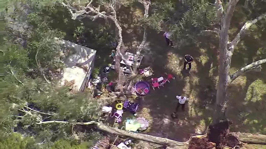 Aerial views show people working to stabilize a tree that fell on a woman's home Monday morning and killed her. 