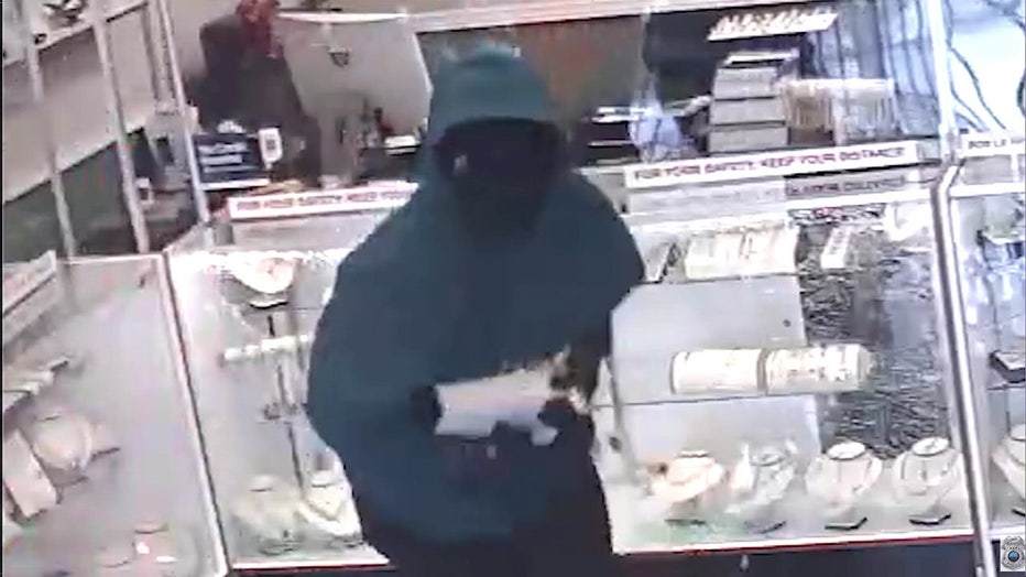 A man in a hoodie is seen on video smashing a display case at the store. 