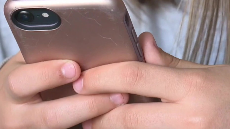 File: Teen hands grip cell phone. 