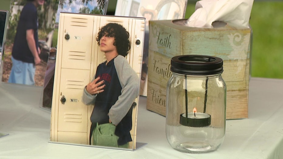 Image of Jakub Lopez next to cards and candle at vigil in his memory. 