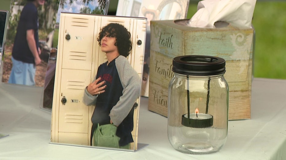 Image of Jakub Lopez next to cards and candle at vigil in his memory.