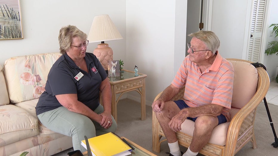 Case worker sits with a man whose home was damaged by Hurricane Ian.