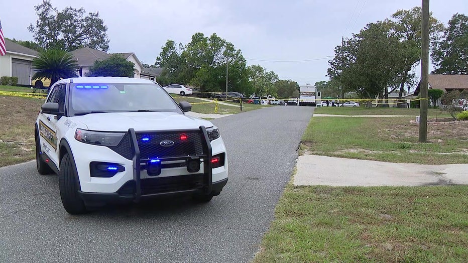 Patrol vehicle and crime scene tape outside scene of fatal home inversion.