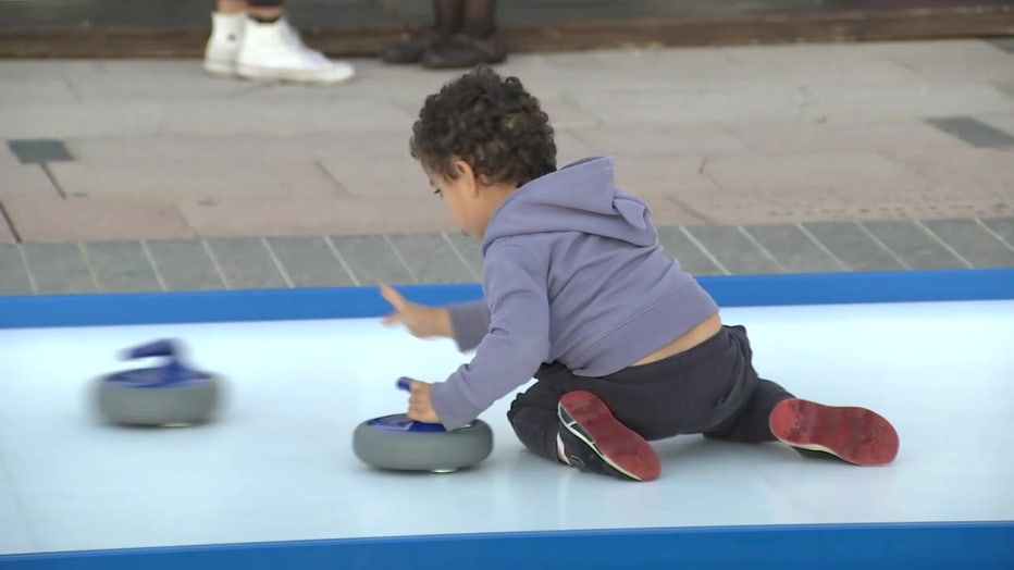 A child plays on the ice-less curling court. 