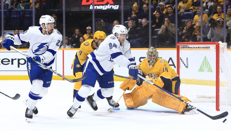 NASHVILLE, TN - DECEMBER 07: Tampa Bay Lightning left wing Tanner Jeannot (84) attempts to play the deflected puck as Nashville Predators defenseman Roman Josi (59) and goalie Juuse Saros (74) defend during the NHL game between the Nashville Predators and Tampa Bay Lightning, held on December 7, 2023, at Bridgestone Arena in Nashville, Tennessee. (Photo by Danny Murphy/Icon Sportswire via Getty Images)