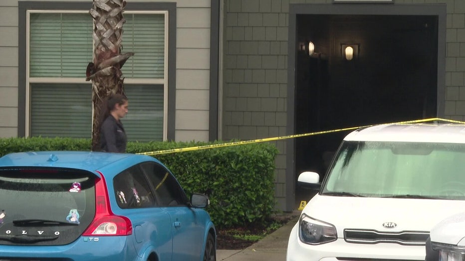 An investigator and crime scene tape outside an apartment where a mother and her teen daughter were stabbed to death. 