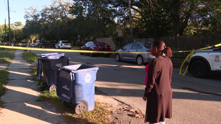 Neighbors stand outside crime scene tape where a mailman was killed in a hit-and-run crash on Monday. 