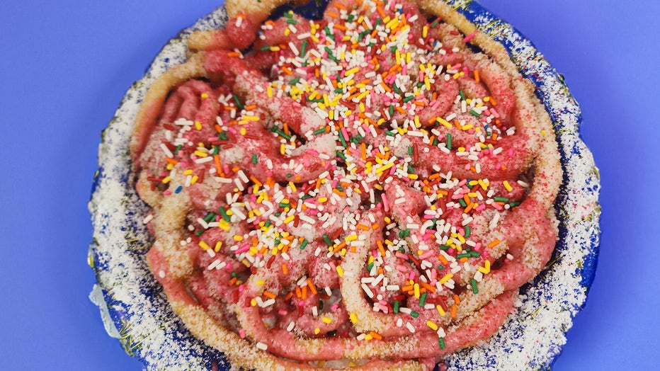 Funnel cake is topped with powdered sugar, pink icing and a variety of sprinkles. Courtesy: Florida State Fair. 