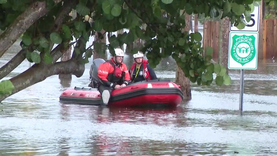 People on a boat travel through flood waters. 