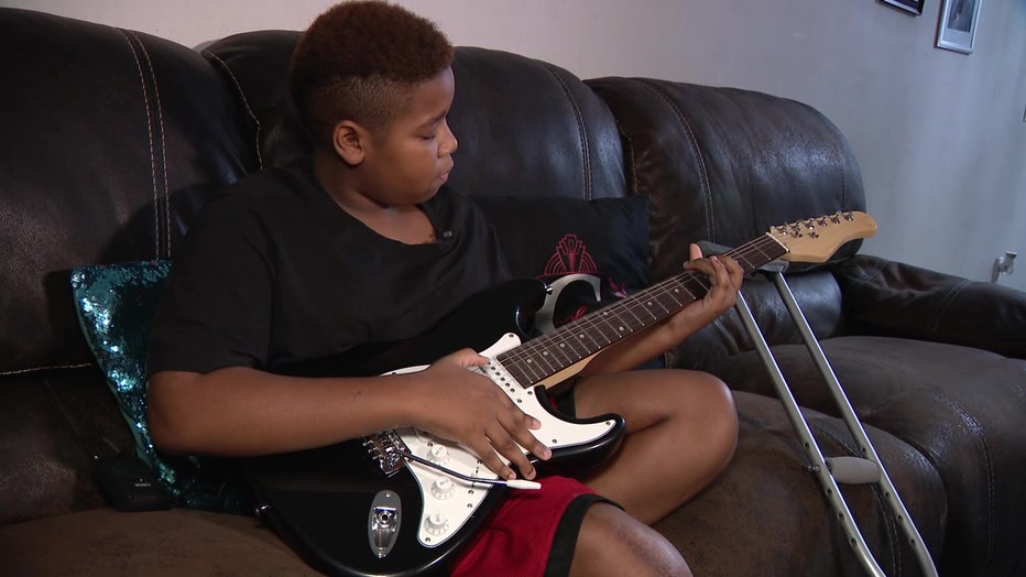 Elijah plays a guitar as he gears up to battle cancer again. 