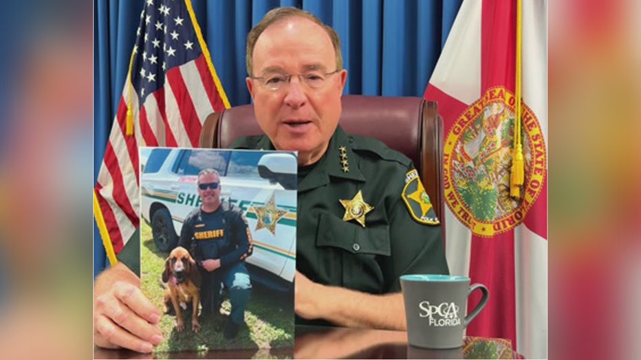 Polk County Sheriff Grady Judd holds up an image of K-9 Wyatt and Deputy Rimes. 