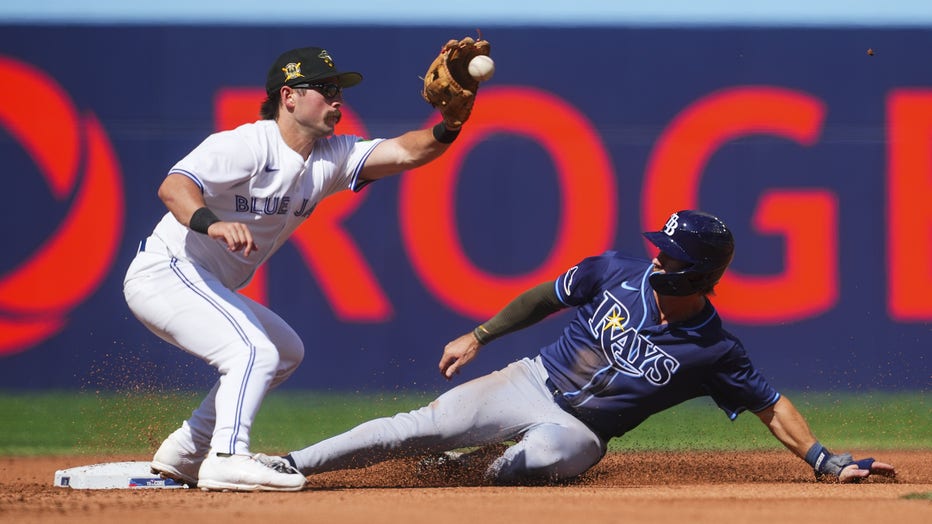 TORONTO, ON - MAY 18: Jonny DeLuca #21 of the Tampa Bay Rays steals second base against Davis Schneider #36 of the Toronto Blue Jays during the fourth inning in their MLB game at the Rogers Centre on May 18, 2024 in Toronto, Ontario, Canada. (Photo by Mark Blinch/Getty Images)