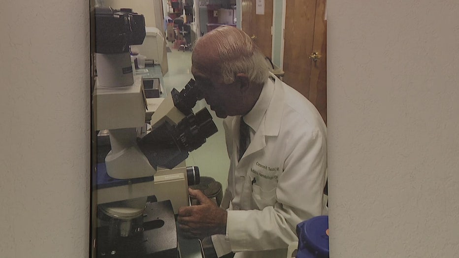 Dr. Cameron Tebbi studying potential pediatric leukemia vaccine through a microscope.