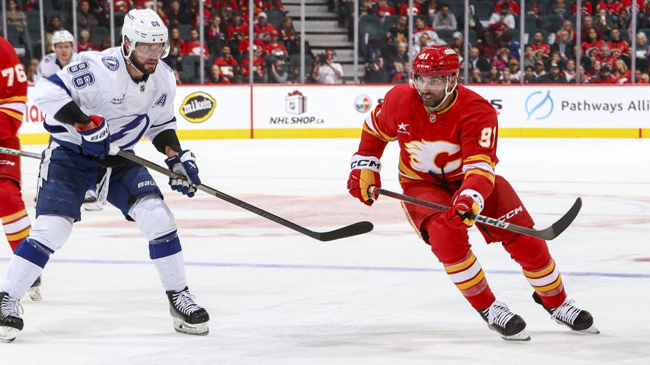 CALGARY, AB - DECEMBER 12: Nazem Kadri #91 of the Calgary Flames battles for the puck against Nikita Kucherov #86 of the Tampa Bay Lightning at Scotiabank Saddledome on December 12, 2024 in Calgary, Alberta, Canada. (Photo by Gerry Thomas/NHLI via Getty Images)