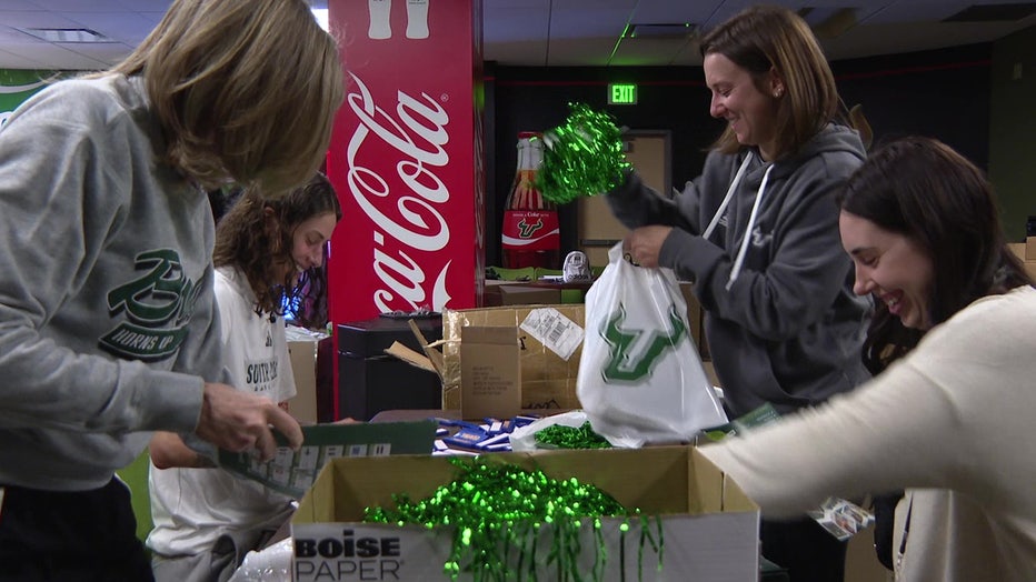 Players on the USF Bulls women's basketball team help to fill up goody bags given to students at the game.