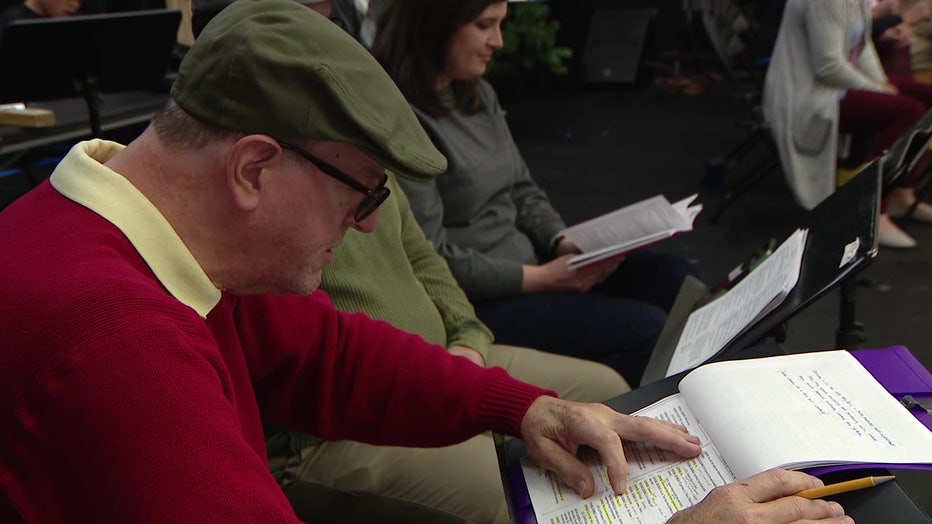 An actor reads from his script as he performs "It’s a Wonderful Life" into a microphone for the radio.