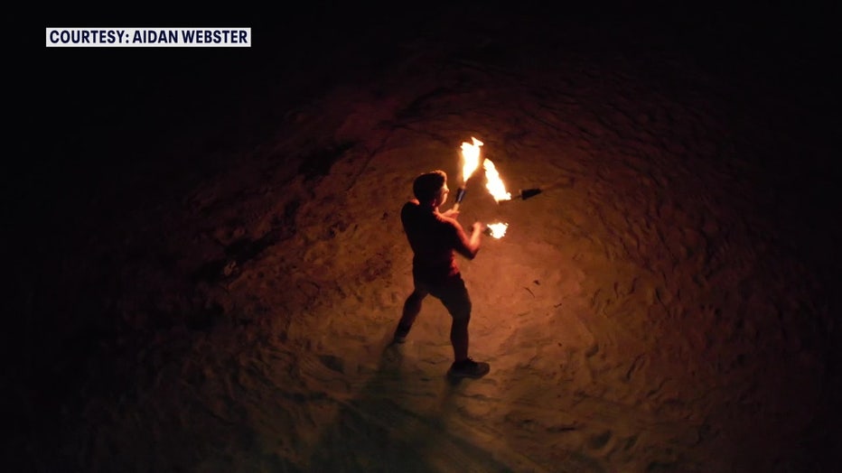 Aidan Webster haciendo malabares con antorchas de llamas.