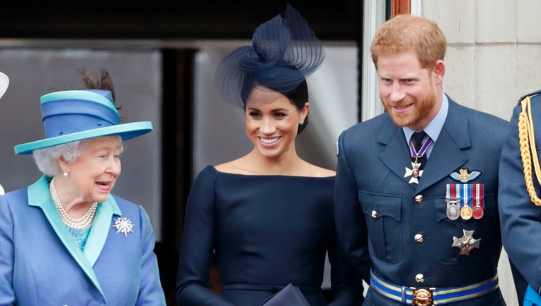 ) Queen Elizabeth II, Meghan, Duchess of Sussex and Prince Harry, Duke of Sussex watch a flypast to mark the centenary of the Royal Air Force from the balcony of Buckingham Palace on July 10, 2018 in London, England.