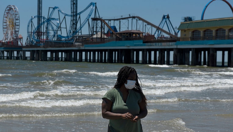 A woman wears a mask on the beach after it was reopened on May 1, 2020 in Galveston, Texas. As part of phase one Gov. Greg Abbott reopened the beaches to the public Friday along with restaurants and retailers. 