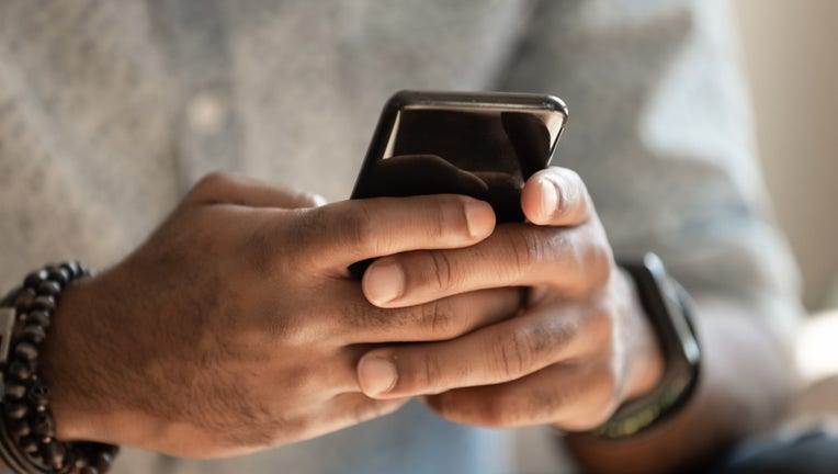 FILE - Man holding smartphone to text stock image.