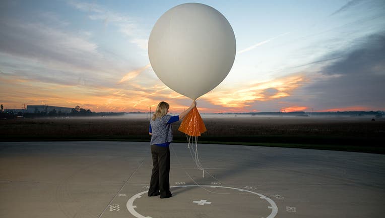 A meteorologist releases a balloon attached to weather and altitude recording and transmitting devices.