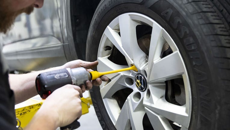 FILE - A worker uses an impact driver to change a tire at a CarMax dealership in Albany, New York, US, on Wednesday, Dec. 13, 2023. Photographer: Angus Mordant/Bloomberg via Getty Images