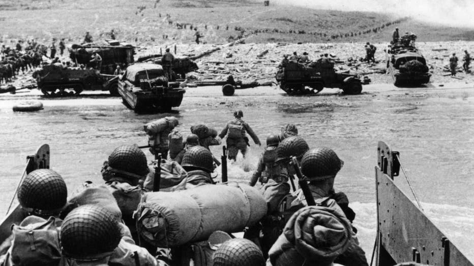 American assault troops and equipment landing on Omaha beach on the Northern coast of France, the smoke in the background is from naval gunfire supporting the attack. 