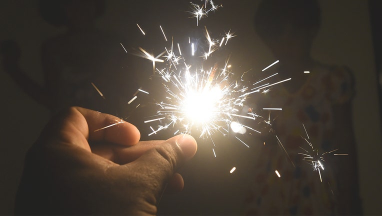 A burning sparkler is held. The chemicals in sparklers and other fireworks can cause serious harm to pets if ingested.